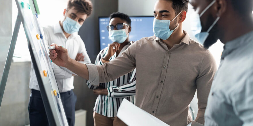 Man in protective face mask presenting business strategy on whiteboard